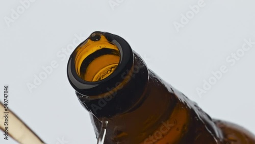 Uncorking glass beer bottle closeup. Foamy carbonated cider pouring from flask photo