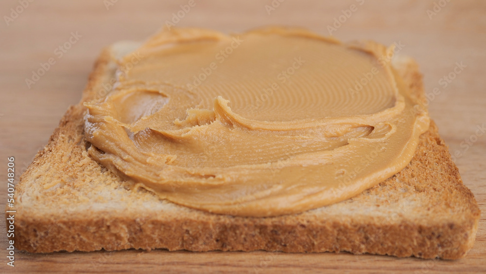Breakfast with peanut butter. Peanut Butter Spreading on bread, close up Breakfast with peanut butter. Peanut Butter Spreading on bread, close up