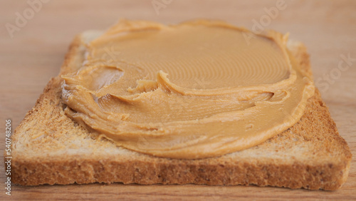 Breakfast with peanut butter. Peanut Butter Spreading on bread, close up