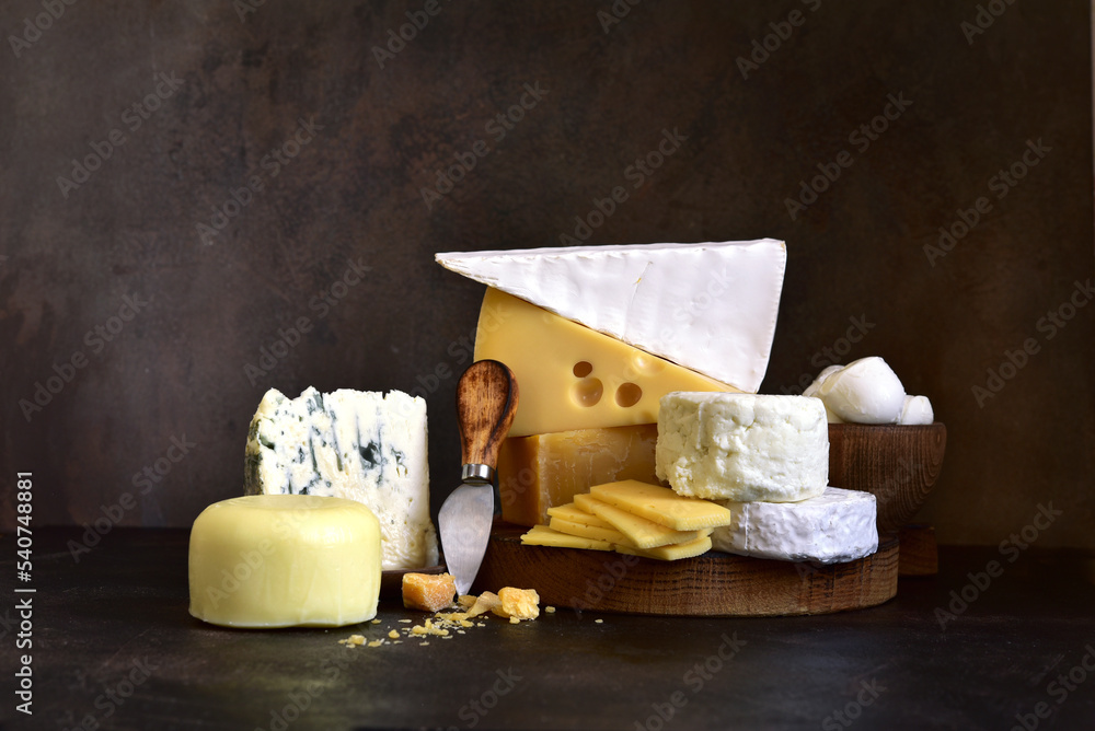 Stack of different types of cheese : camembert, bree, parmesan, mozzarella .