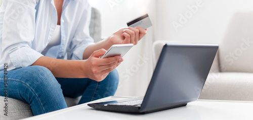 Shopping online at home. Woman paying with laptop and smartphone by credit card for delivery purchases. Girl buy insurance  investing. Technology lifestyle for finance  e-commerce. Close up of hands