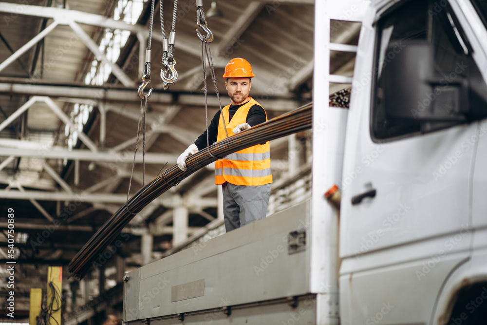Fototapeta premium Man working at steel factory by th crane lifting steel