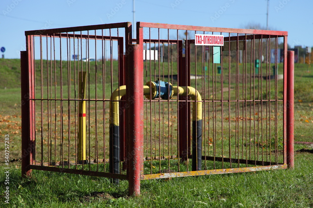 Gas pipe behind the red fence . Inscription in Russian: GAS - FLAMMABLE Gas pipe behind the red fence . Inscription in Russian: GAS - FLAMMABLE