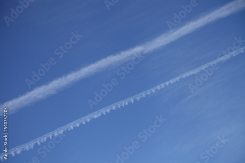 Clear blue sky with two diagonal aircraft vapor exhaust background texture © Ilya