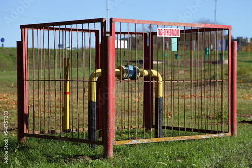 Gas pipe behind the red fence . Inscription in Russian: GAS - FLAMMABLE