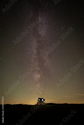 Long exposure view of the Milky Way on field with car rooftop tent