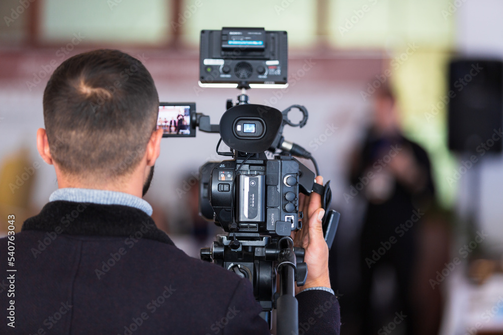 A man and a professional camera shoots a conference