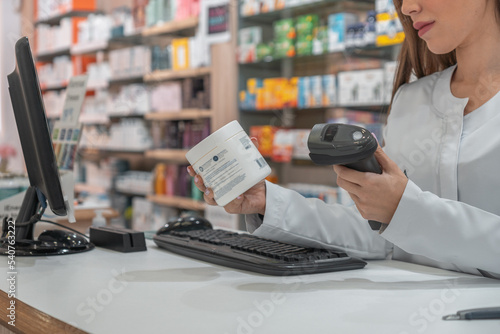 Mujer farmacéutica irreconocible, usando el lector de código de barras, para ver la información del producto.