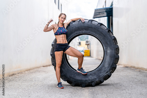 Sportswoman with large tire showing bicep photo
