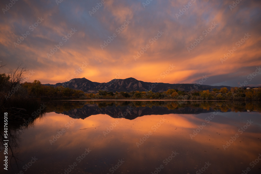 Sunrise over the flatirons with a lake reflection