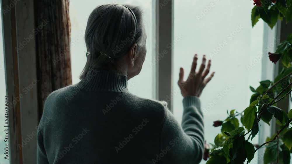 Old woman looking outside the window Old woman looking outside the window