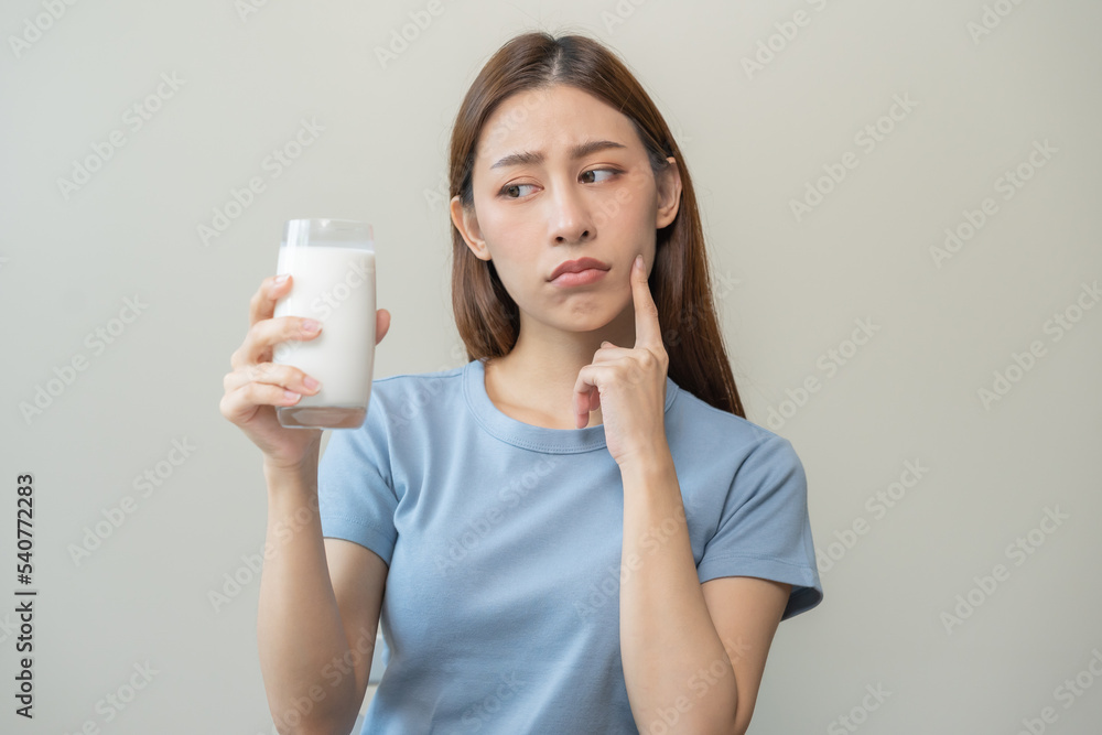 Allergy asian young woman, girl looking, holding glass of milk, face in