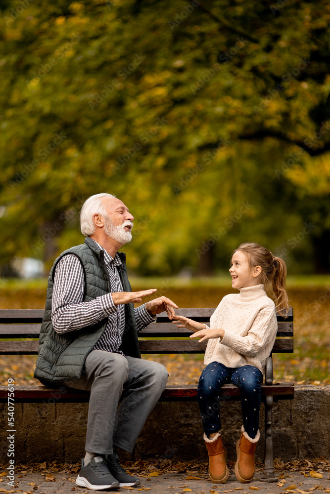 Grandfather playing red hands slapping game with his granddaughter in park on autumn day Grandfather playing red hands slapping game with his granddaughter in park on autumn day