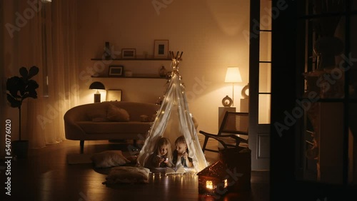 Happy family. Two children girl and boy are reading book in tent. Flashlight in hands of brother and sister. Happy family with book in tent. Children holds. reading book in selfmade house at bedroom photo