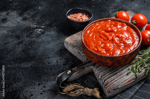 Tomato sauce passata - traditional sauce for italian cuisine. Black background. Top view. Copy space