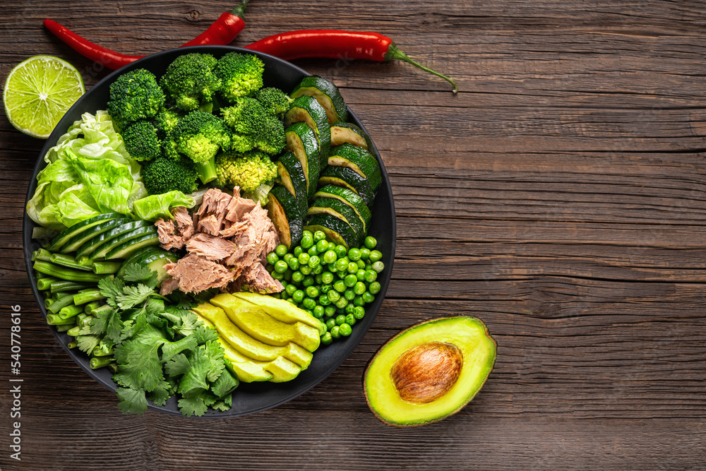 Salad with tuna, broccoli, avocado, green peas, zucchini, cucumber,chile, lime. Healthy Food Bowl. Top view with copy space.