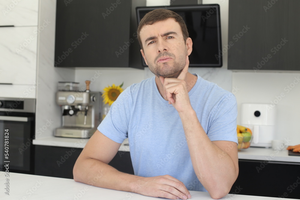 Suspicious looking man thinking in the kitchen Suspicious looking man thinking in the kitchen