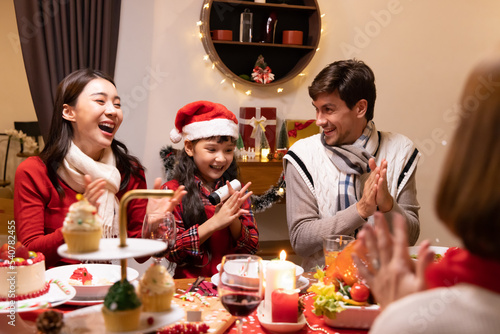 Multi-ethnic family having fun and enjoying indoor party on dinner table at home  New Year party or Christmas
