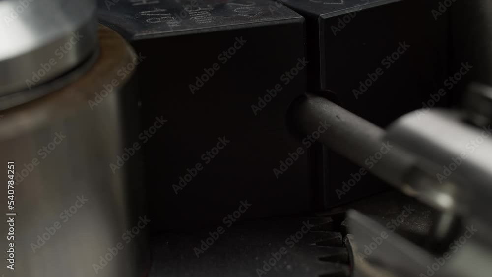 Pulling metal wire rope through machine tool with cog wheels macro view. Steel product processing in plant workshop Pulling metal wire rope through machine tool with cog wheels macro view. Steel product processing in plant workshop