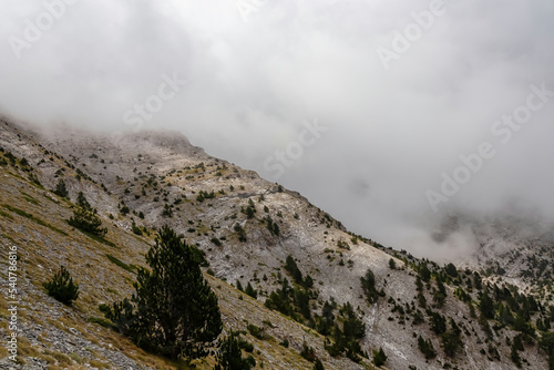 Panoramic view of the cloud covered slopes and rocky ridges of Mount Olympus in Mt Olympus National Park, Thessaly, Greece, Europe. Trekking on hiking trail through mystical fog. Wanderlust