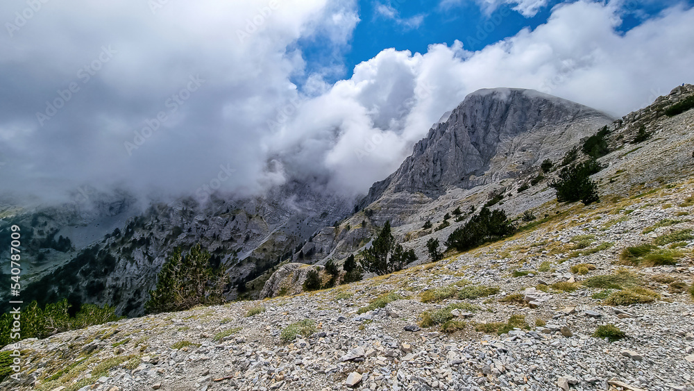 Panoramic view of the cloud covered slopes and rocky ridges of Pieria Mountains near Mount Olympus in Mt Olympus National Park, Thessaly, Greece, Europe. Trekking on hiking trail through mystical fog Panoramic view of the cloud covered slopes and rocky ridges of Pieria Mountains near Mount Olympus in Mt Olympus National Park, Thessaly, Greece, Europe. Trekking on hiking trail through mystical fog