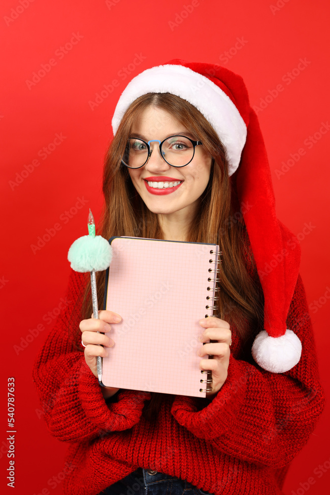 Vertical portrait of a beautiful woman holding a Christmas wish list in her hands on a red background. Vertical portrait of a beautiful woman holding a Christmas wish list in her hands on a red background.