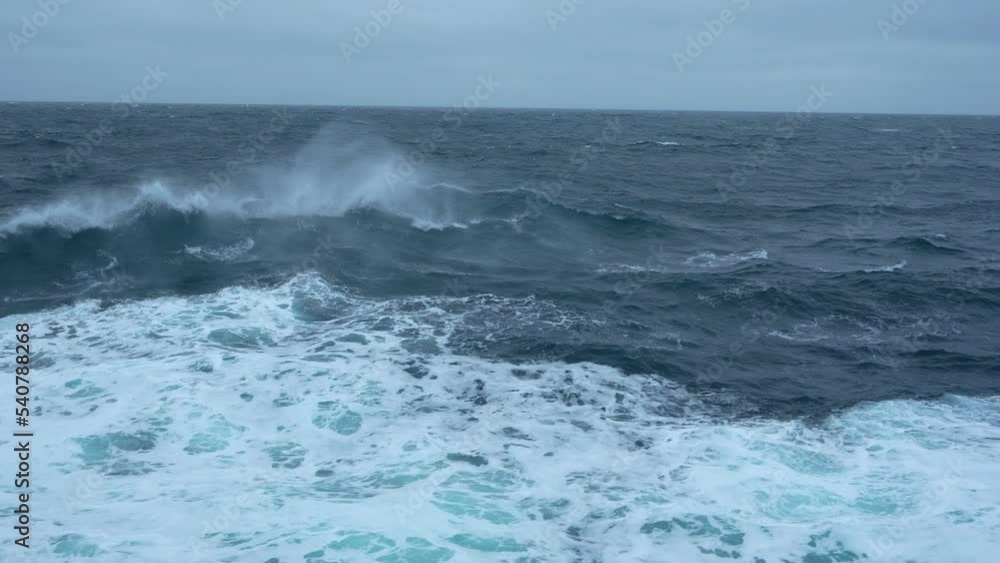 Storm at sea. High waves. Wind blows spray off wave. Side view along ship. Wind breaks waves with white foam. Slow motion Storm at sea. High waves. Wind blows spray off wave. Side view along ship. Wind breaks waves with white foam. Slow motion