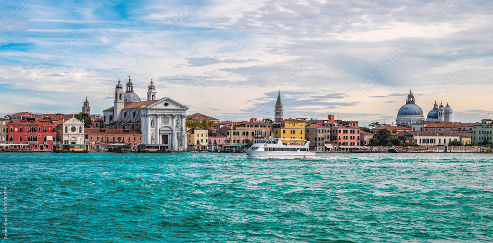 Panoramic view of colorful buildings and church along the Giudecca canal in Venice, Italy.