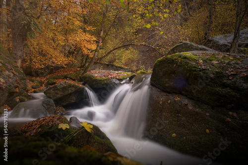 Long exposure of a waterfall of a river surrounded by autumn foliage. Scenic and relaxing image. River Po  Italy.