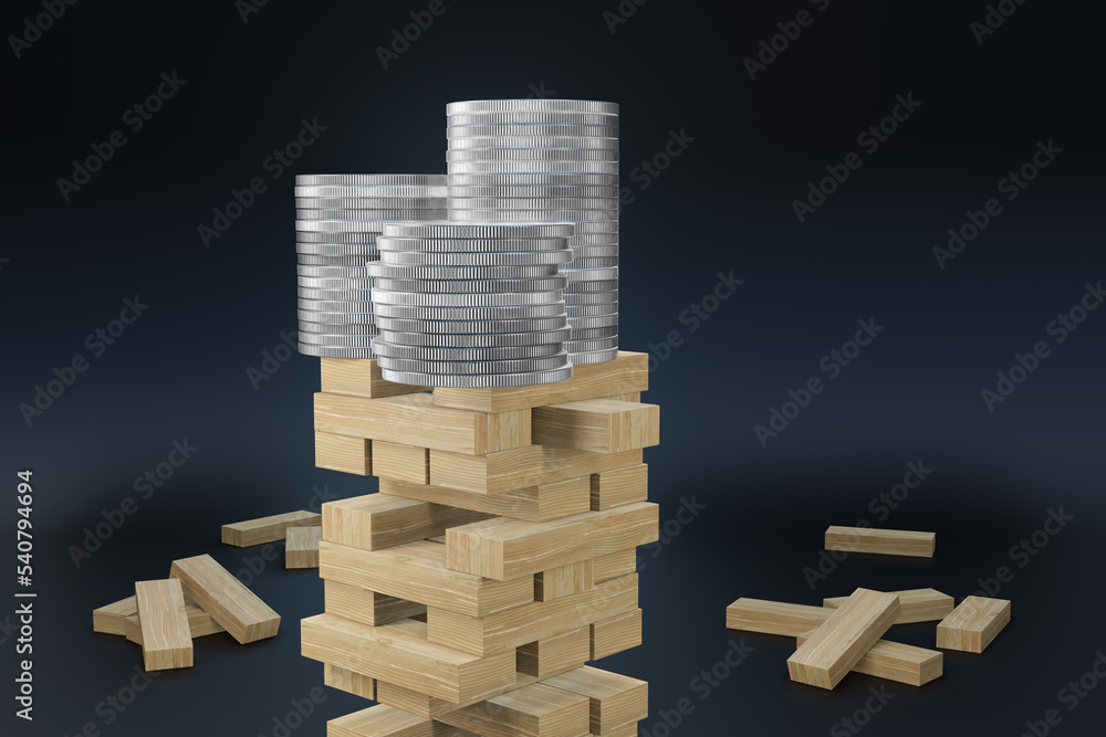 Stacks of silver coins on top of a tower of gaming wooden blocks on dark background. Illustration of the concept of the risk of financial investment and economic recession