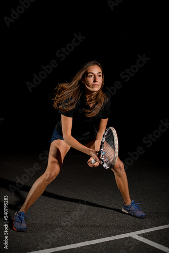 Close-up view on beautiful athletic woman with racket in special pose which preparing to hit tennis ball