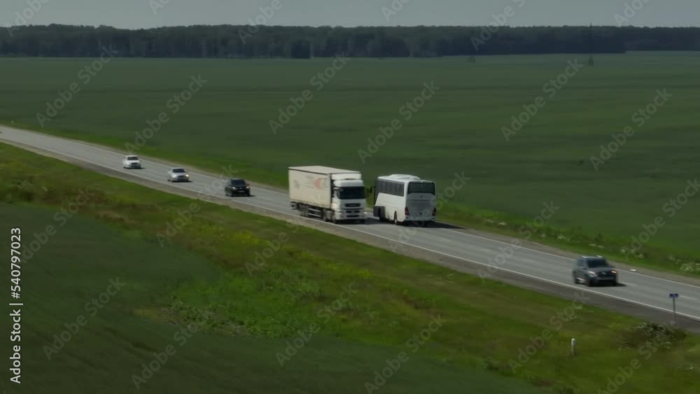 Travel tour bus driving alone on straight highway through plain field. White bus fast speed moving on freeway. Aerial drone wide shot at summer sunny day. Travel tour bus driving alone on straight highway through plain field. White bus fast speed moving on freeway. Aerial drone wide shot at summer sunny day.