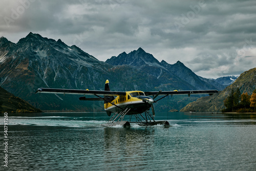 pilot alaska float plane in lake near by mountains blue water wilderness flying cloudy weather in autumn fall
