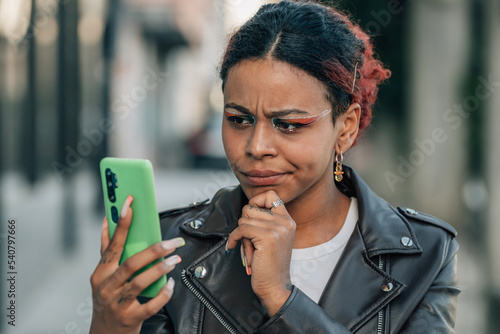 woman in the street with mobile phone and expression of doubt or mistrust