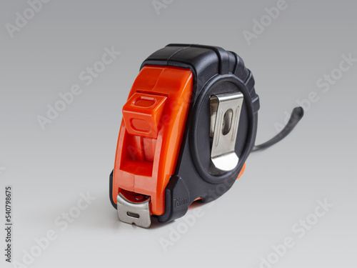 Measuring tape measure in a black and orange case on a light background