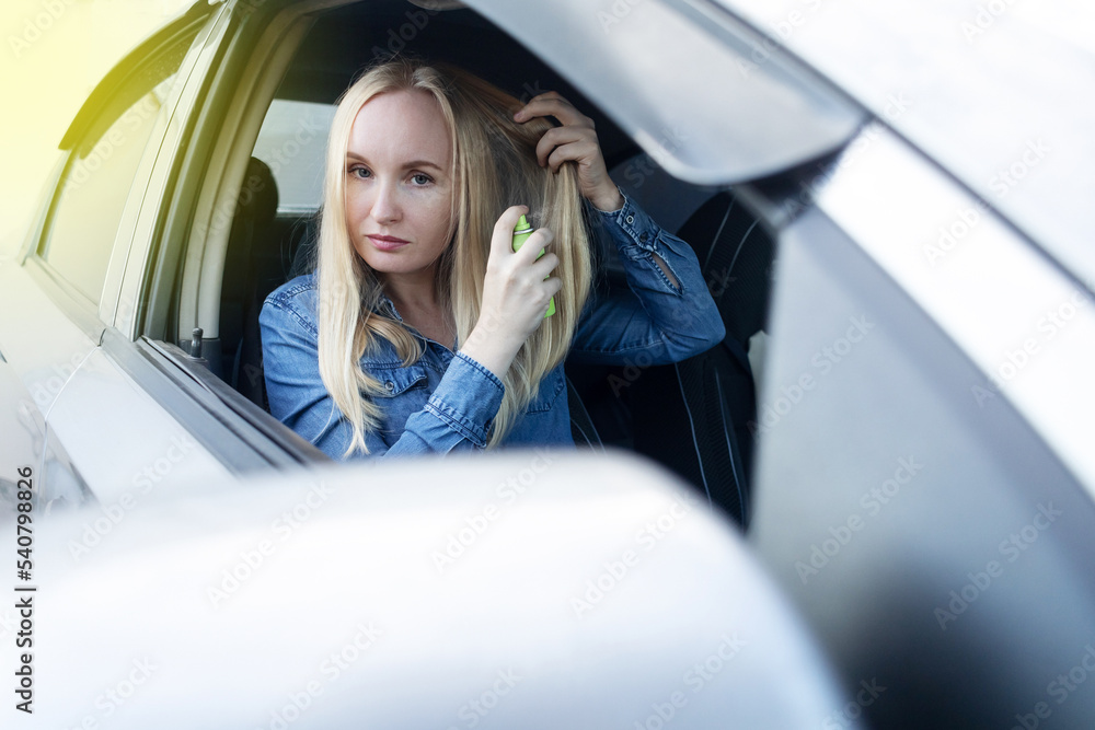 Dry shampoo. Blonde girl sprays shampoo on her hair. The problem of oily  hair while traveling. An emergency remedy for excessive sebum production.  Make your head clean without water Stock Photo |
