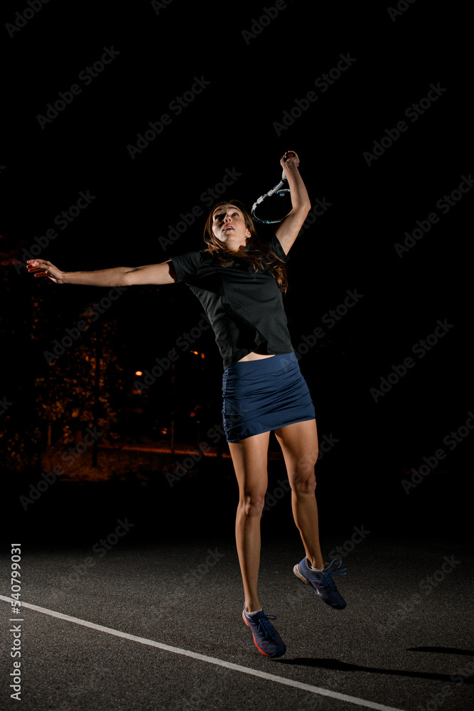 active female tennis player with tennis racket in her hand bouncing to hit the tennis ball.