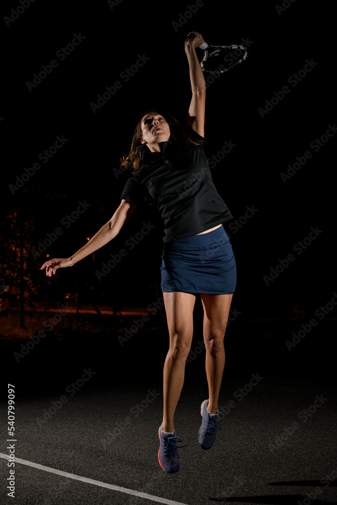 female tennis player with tennis racket in her hand bouncing to hit the tennis ball.