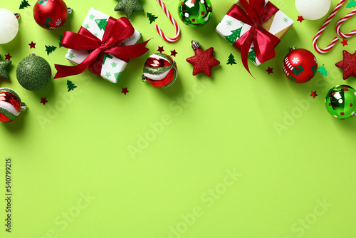 Stylish Christmas ornaments and gift boxes frame top border. Xmas decorations on pastel green background. Top view, flat lay. photo