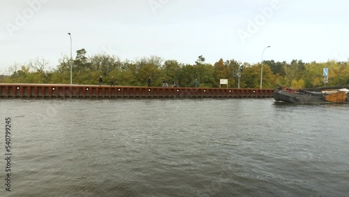 a historical boat travels on the canal of a trough bridge, which is filled with water and crosses a natural river as a shipping lane