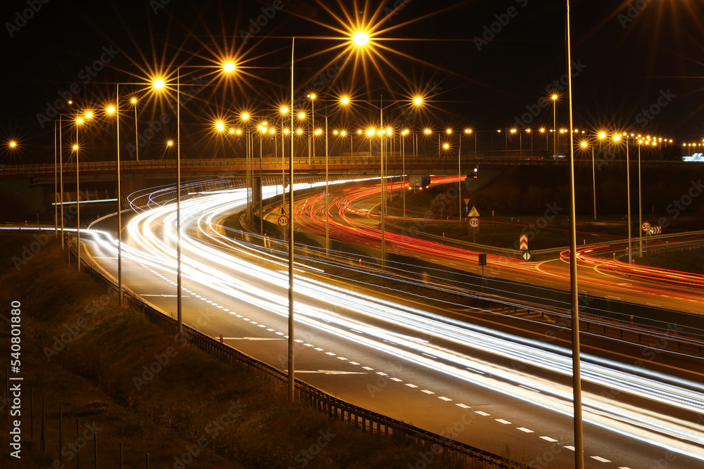 Autostrada samochodowa nocą ze smugami po przejeżdżających pojazdach.  - obrazy, fototapety, plakaty 