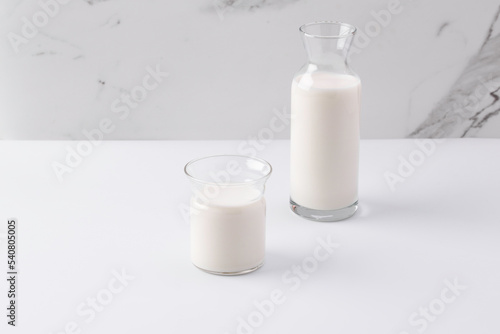 glass and jug with milk on white background