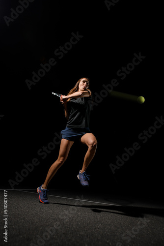 action shot of flying tennis ball and athletic woman with racket backhand