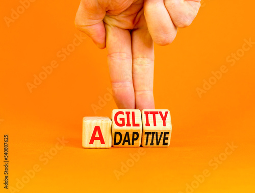 Agility and adaptive symbol. Concept words Agility and Adaptive on wooden cubes. Beautiful orange table orange background. Businessman hand. Business agility and adaptive concept. Copy space. photo