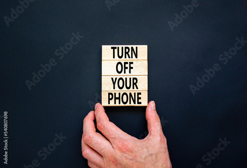 Turn off your phone symbol. Concept words Turn off your phone on wooden blocks. Beautiful black table black background. Businessman hand. Business psychological turn off your phone concept. Copy space