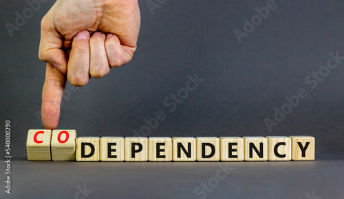Codependency or dependency symbol. Concept words Codependency and dependency on wooden cubes. Psychologist hand. Beautiful grey background. Psychological codependency dependency concept. Copy space.