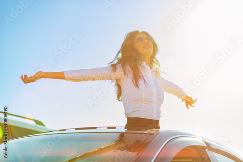 Pretty woman out of a car's hatch against sunset sky