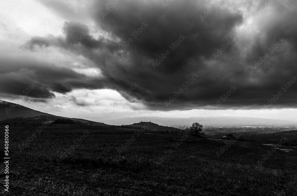 Distant view of Assisi Umbria Italy beneath moody, menacing clouds