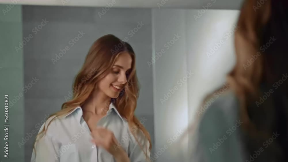 Happy young blonde woman smiling while looking at mirror in bathroom. Happy young blonde woman smiling while looking at mirror in bathroom.