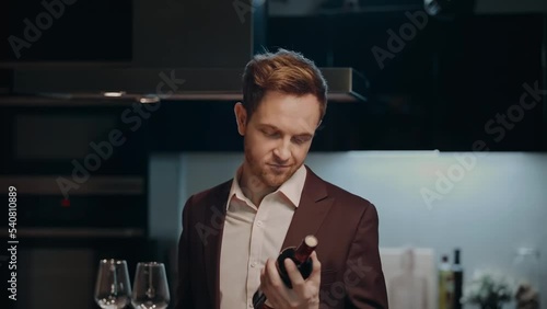 A young man in a suit opens red wine during a date at home. A young man opens a bottle of wine.